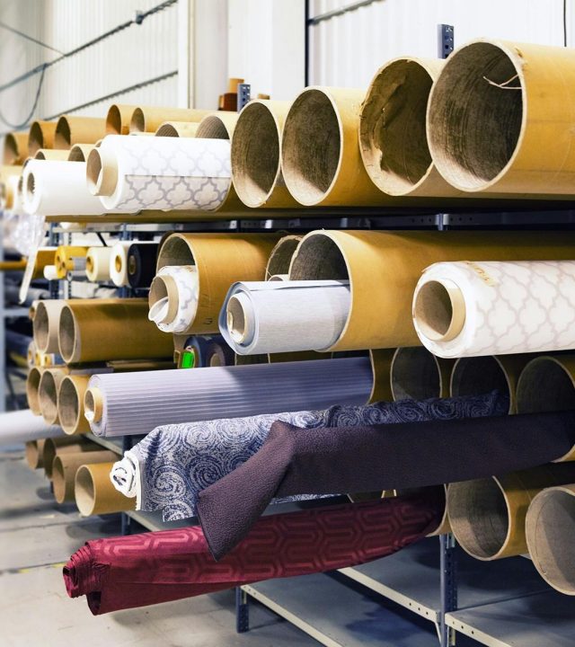 Rows of textile rolls stored in a factory for industrial manufacturing.