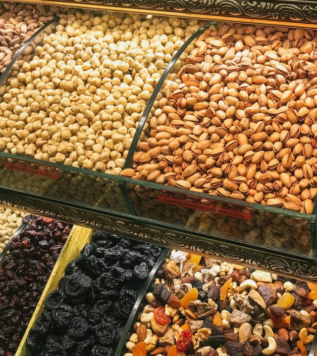 Colorful assortment of nuts and dried fruits in a market display, showcasing healthy snack options.